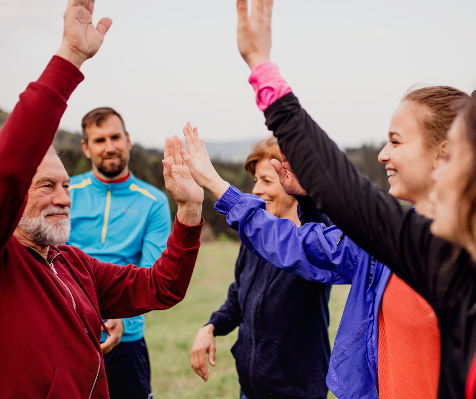 Grupo multigeneracional celebrando al aire libre tras una actividad física, simbolizando los beneficios sociales y emocionales del ejercicio para una vida larga y saludable.
