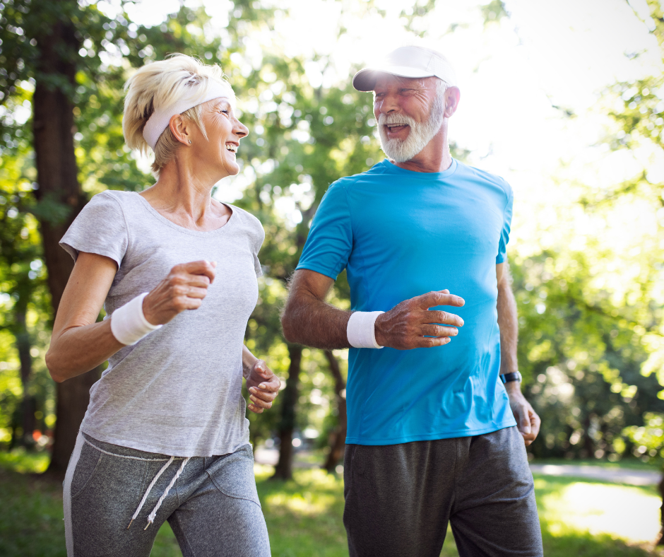 Pareja de adultos mayores corriendo al aire libre y sonriendo, disfrutando de una vida activa y saludable mientras fortalecen su capacidad cardiovascular.