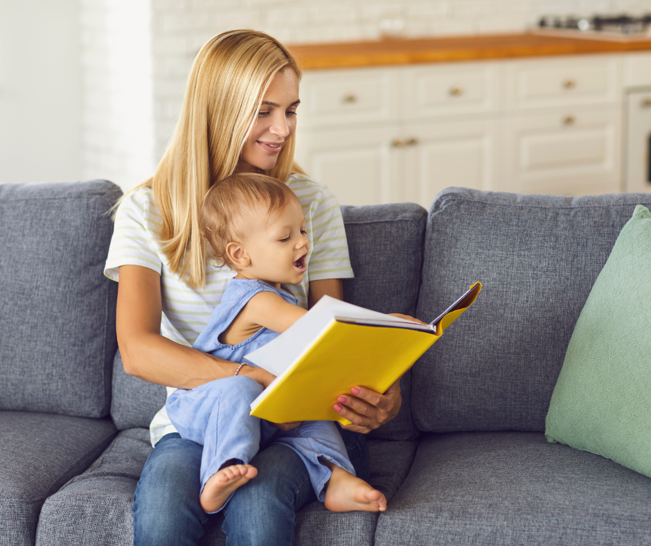 Madre joven con su bebé en brazos leyendo un libro, representando la maternidad temprana y su impacto en la salud y el envejecimiento a largo plazo.