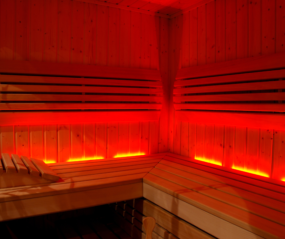 Interior de sauna infrarrojo con luz roja, mostrando un ambiente relajante y beneficios para la salud, la circulación y la longevidad.
