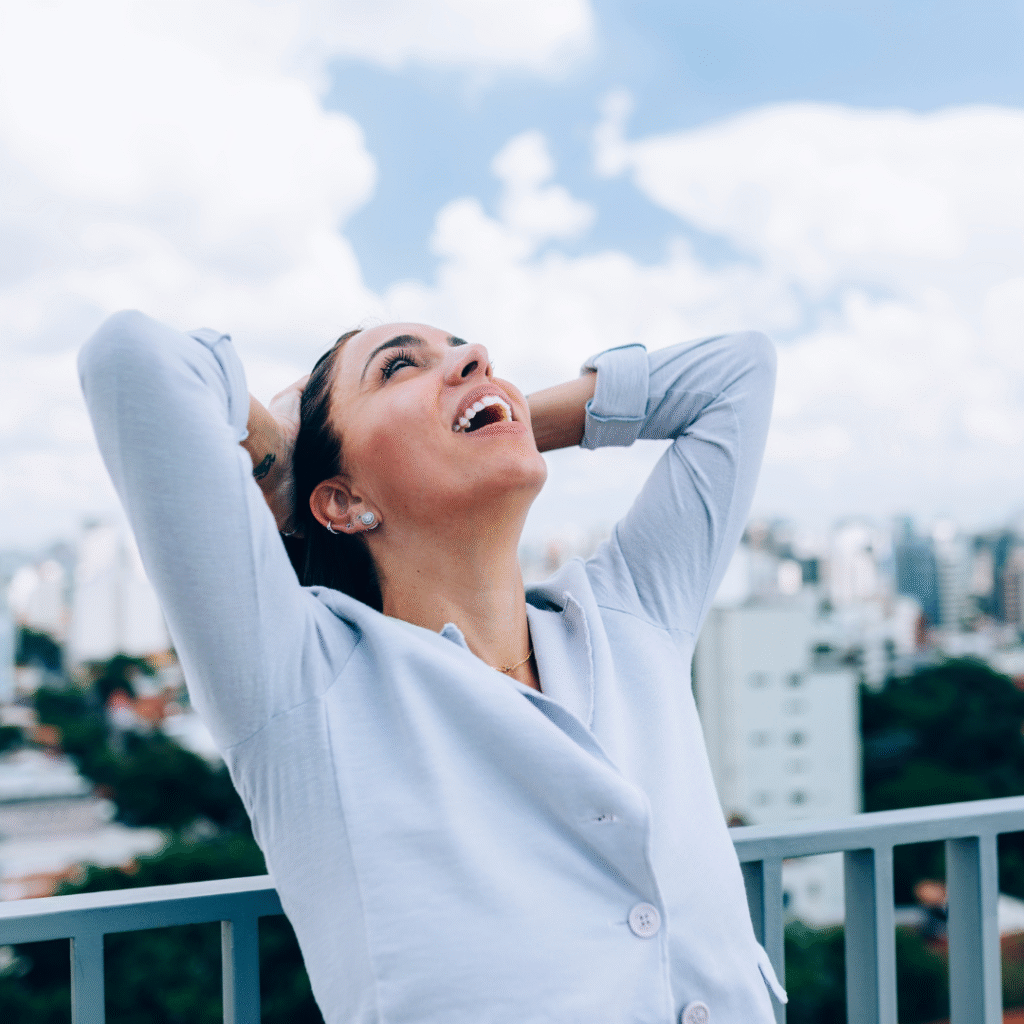 Mujer sonriendo al aire libre con sensación de alivio y libertad tras superar migraña.